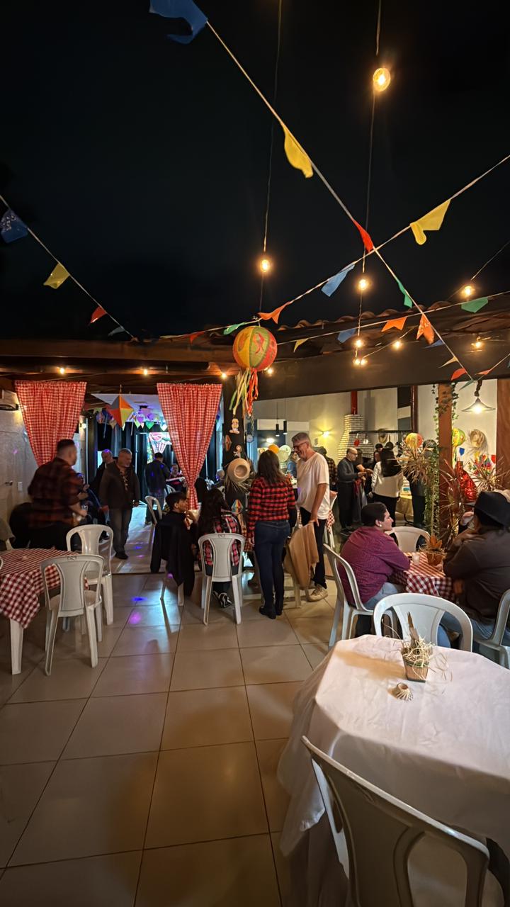 Festa junina no Espaço Meneghelli, com bandeirinhas coloridas, mesas de toalha xadrez e convidados